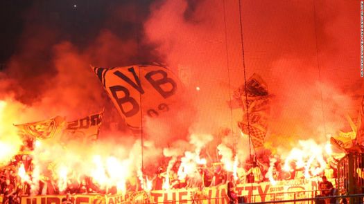 Los ultras del Dortmund en medio de bengalas y banderas durante un partido. 